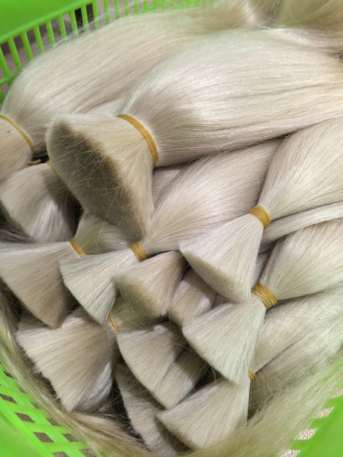 Light-coloured hair bundles grouped in a basket for batch storage